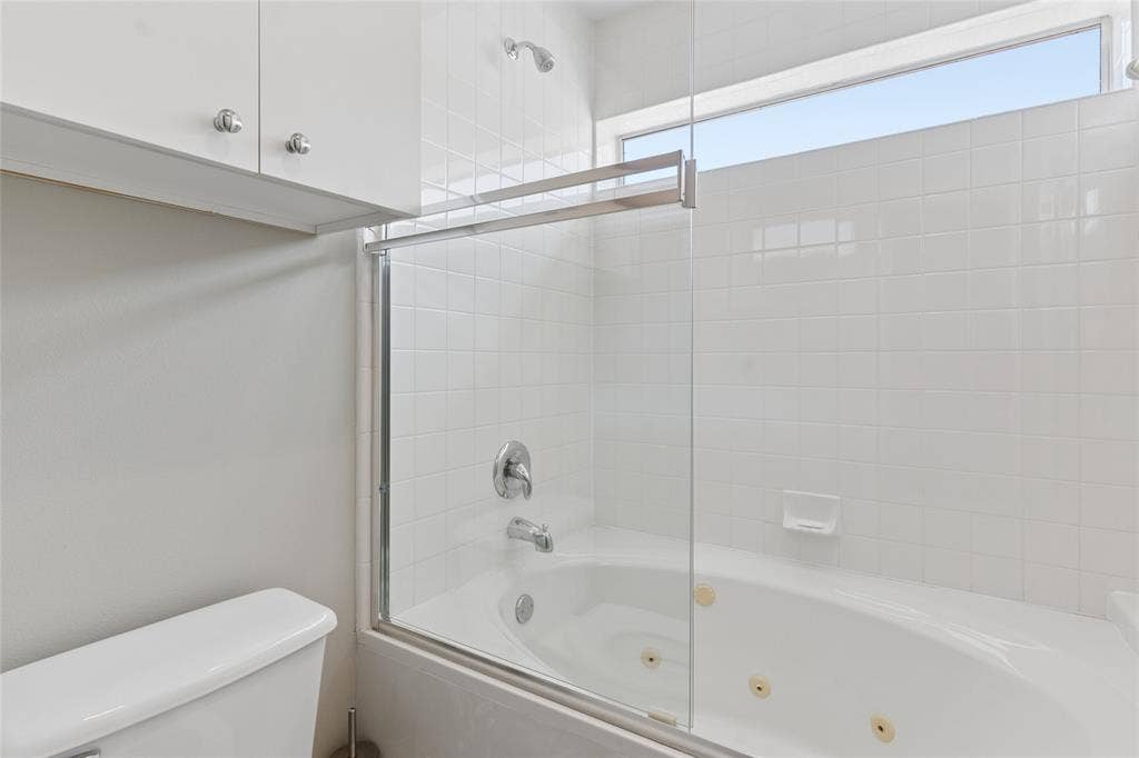 2714 Shelby Avenue, Dallas, TX 75219 Modern bathroom featuring a frameless glass shower enclosure with chrome hardware, ceramic tile surround, and an integrated soaking tub