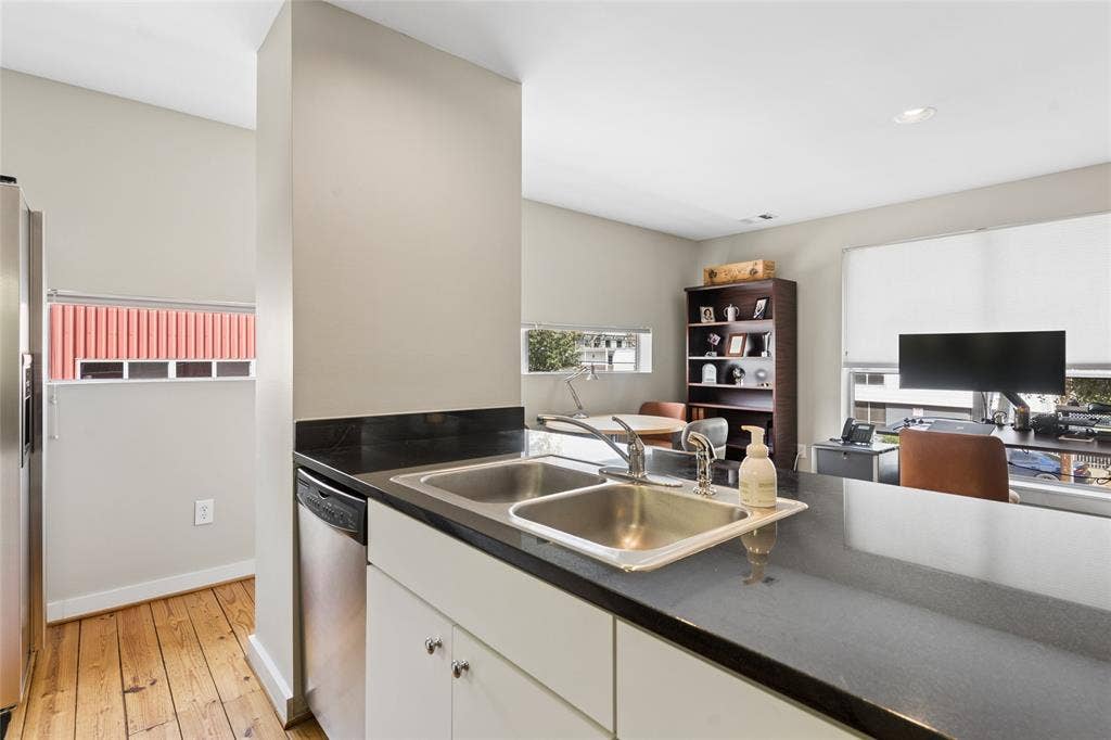 2714 Shelby Avenue, Dallas, TX 75219 Kitchen featuring a double basin stainless steel sink, dark countertops, white cabinetry with silver hardware, and a stainless steel dishwasher