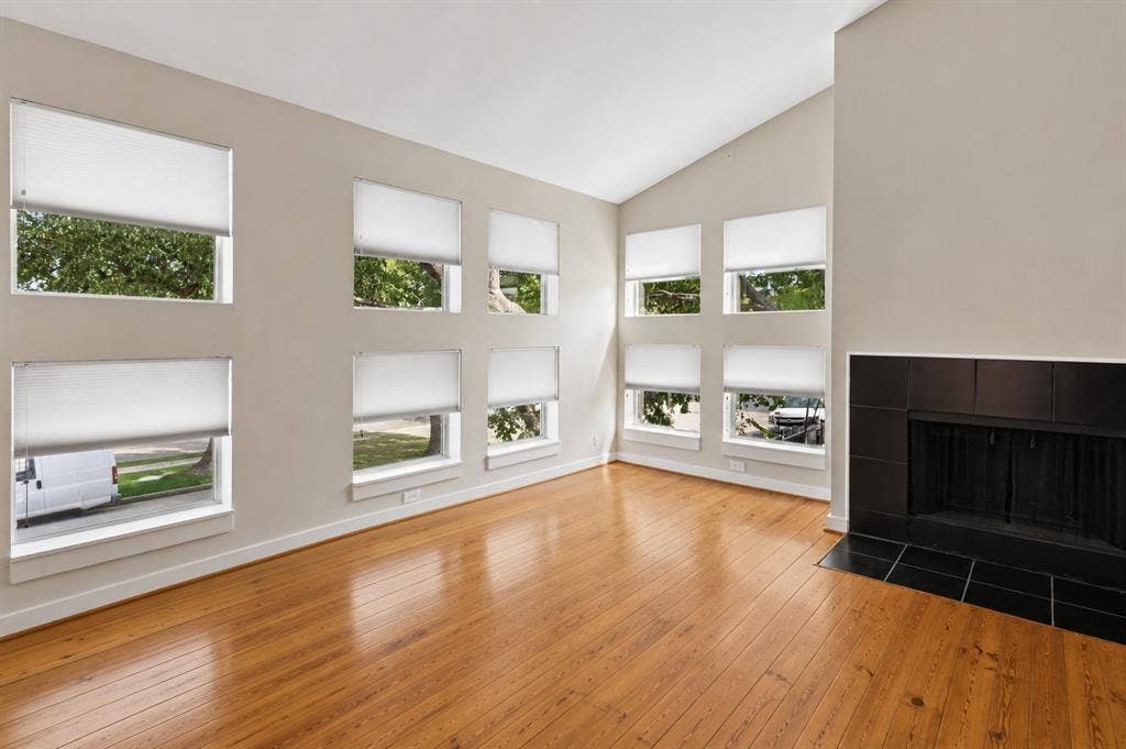 2714 Shelby Avenue, Dallas, TX 75219 Vaulted ceilings, wood-finish flooring, multiple windows, and a black tile fireplace with a hearth