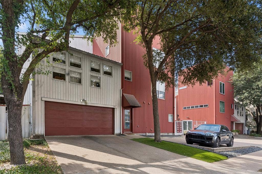 2714 Shelby Avenue, Dallas, TX 75219 Corrugated metal siding, attached garage, multiple windows, concrete driveway, and established trees