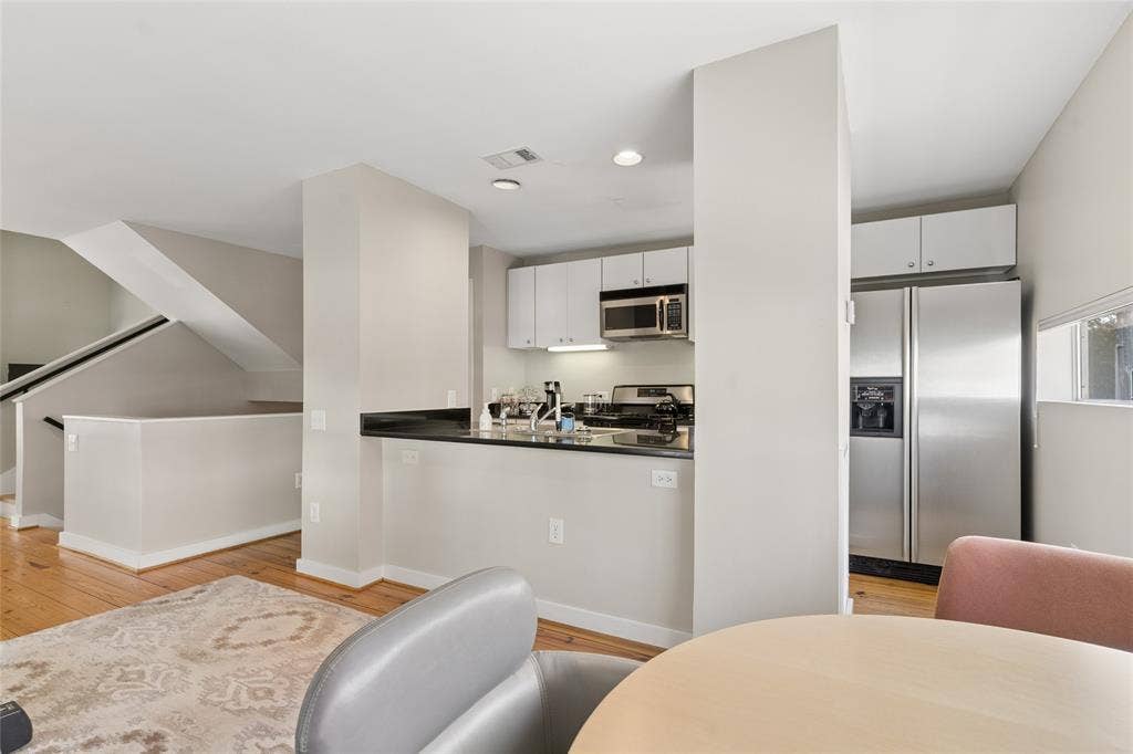 2714 Shelby Avenue, Dallas, TX 75219 Hardwood flooring throughout, contemporary kitchen with stainless steel appliances, white cabinetry, dark countertops, and a built-in microwave