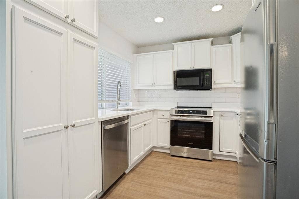 1412 E Park Boulevard, Plano, TX 75074 Kitchen featuring white cabinetry, stainless steel appliances, subway tile backsplash, and light wood-finish flooring