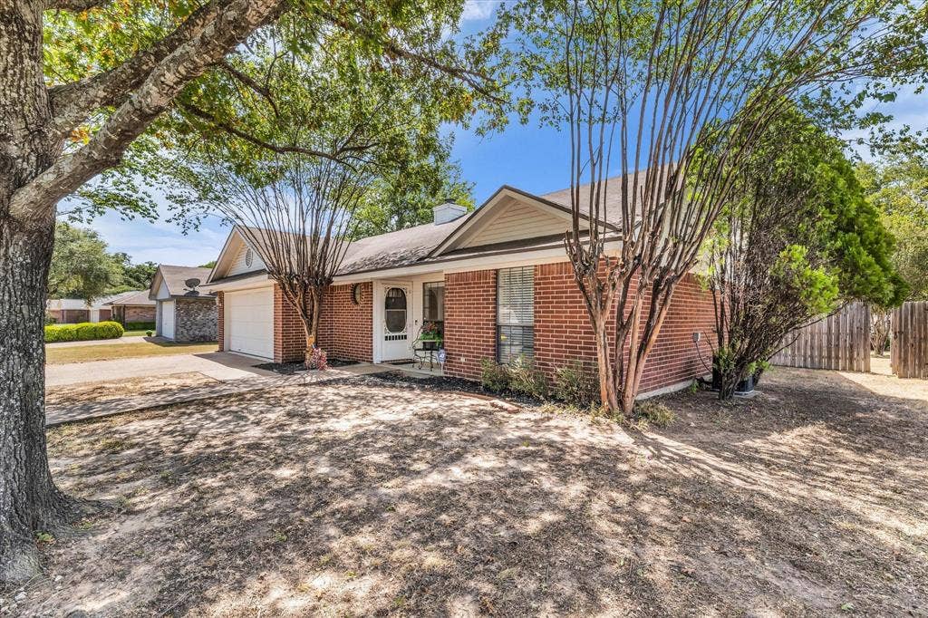 4626 Lexington Street, Bellmead, TX 76705 Brick exterior with white trim, attached garage, and mature trees