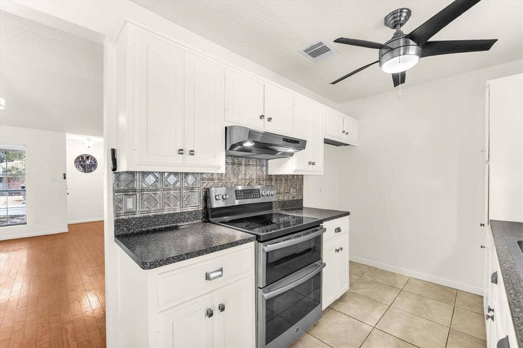4626 Lexington Street, Bellmead, TX 76705 Kitchen featuring white cabinetry, dark speckled countertops, a double-oven range, and a decorative backsplash