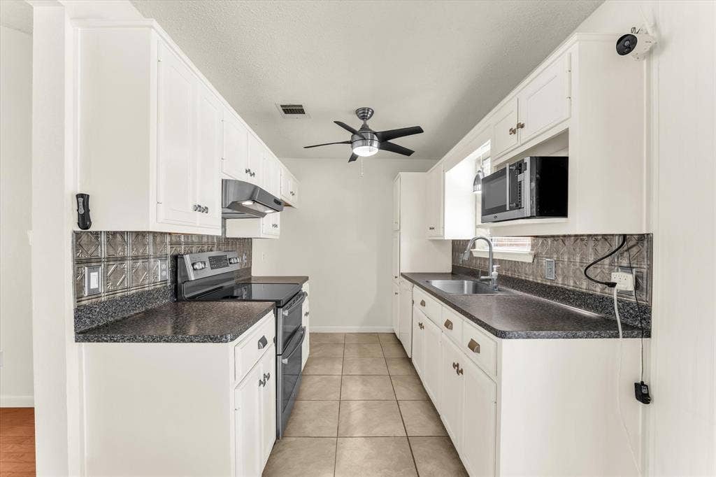 4626 Lexington Street, Bellmead, TX 76705 White cabinetry with gold-tone hardware, dark countertops, and a decorative tile backsplash