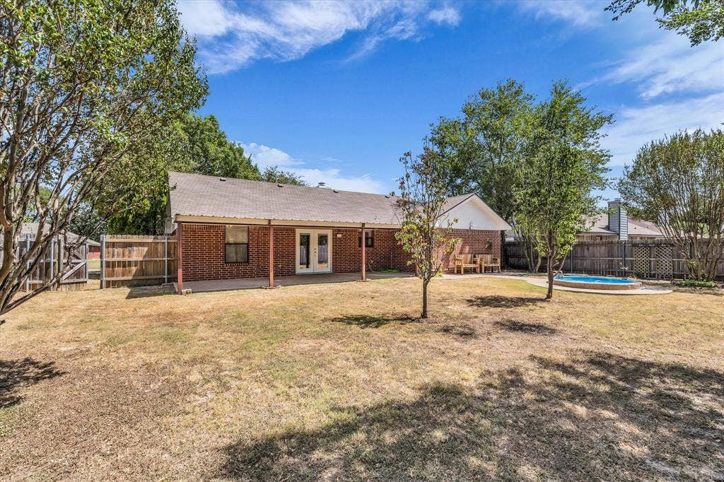 4626 Lexington Street, Bellmead, TX 76705 Red brick exterior with a covered patio, double glass doors, and a fenced perimeter