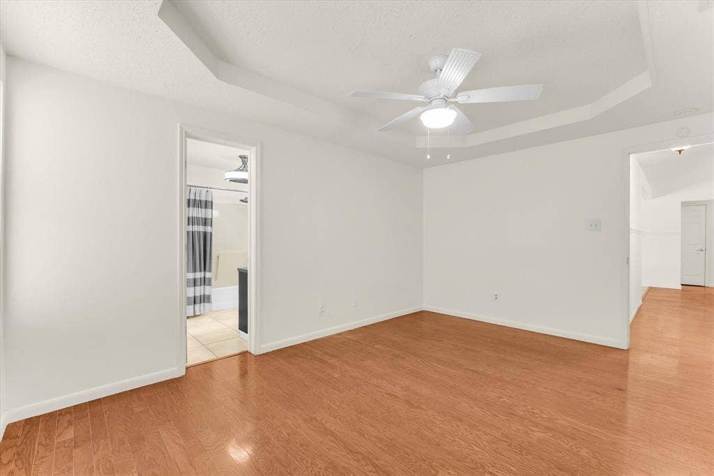 4626 Lexington Street, Bellmead, TX 76705 Tray ceiling with a ceiling fan, light wood-finish flooring, and white walls