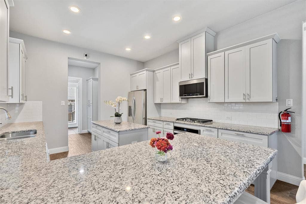 8226 Natchez Trail, Dallas, TX 75252 Contemporary kitchen featuring white cabinetry, light-toned countertops, stainless steel appliances, a white subway tile backsplash, and recessed lighting