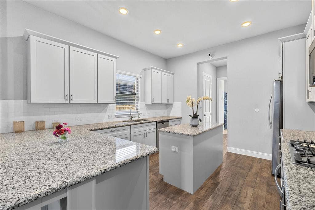 8226 Natchez Trail, Dallas, TX 75252 Kitchen featuring light-toned cabinetry, a central island, granite countertops, wood-finish flooring, and recessed lighting