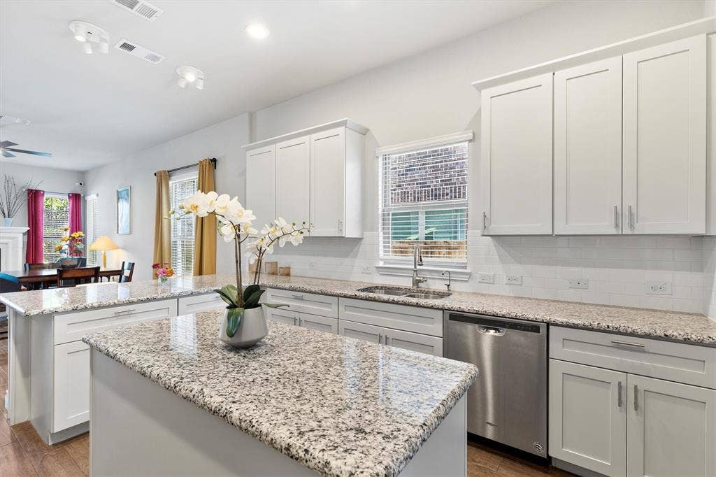 8226 Natchez Trail, Dallas, TX 75252 Kitchen featuring white shaker-style cabinetry, granite countertops, stainless steel dishwasher, and an undermount sink