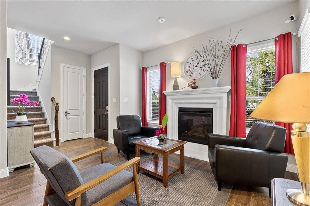 8226 Natchez Trail, Dallas, TX 75252 Living area featuring a fireplace with a white mantel, wood-finish flooring, and a staircase with wood handrails
