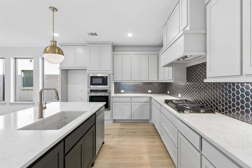 2616 Radiant Way, Celina, TX 75009 Beautiful two tone cabinetry, gorgeous countertops and statement backsplash effortlessly pair with contemporary stainless steel to create a kitchen for the ages!