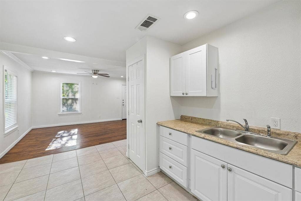 5012 Pamela Drive, Fort Worth, TX 76116 White cabinetry with silver hardware, dual basin stainless steel sink, and light-toned countertop