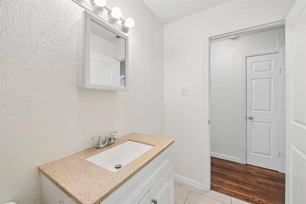 5012 Pamela Drive, Fort Worth, TX 76116 White shaker vanity with integrated sink, patterned countertop, and chrome faucet