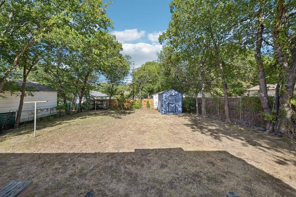 5012 Pamela Drive, Fort Worth, TX 76116 Spacious backyard featuring mature trees, a privacy fence, and a utility shed