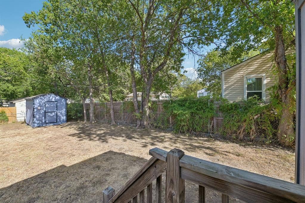 5012 Pamela Drive, Fort Worth, TX 76116 Expansive backyard featuring a storage shed, mature trees, wood fence, and a porch with wood railings
