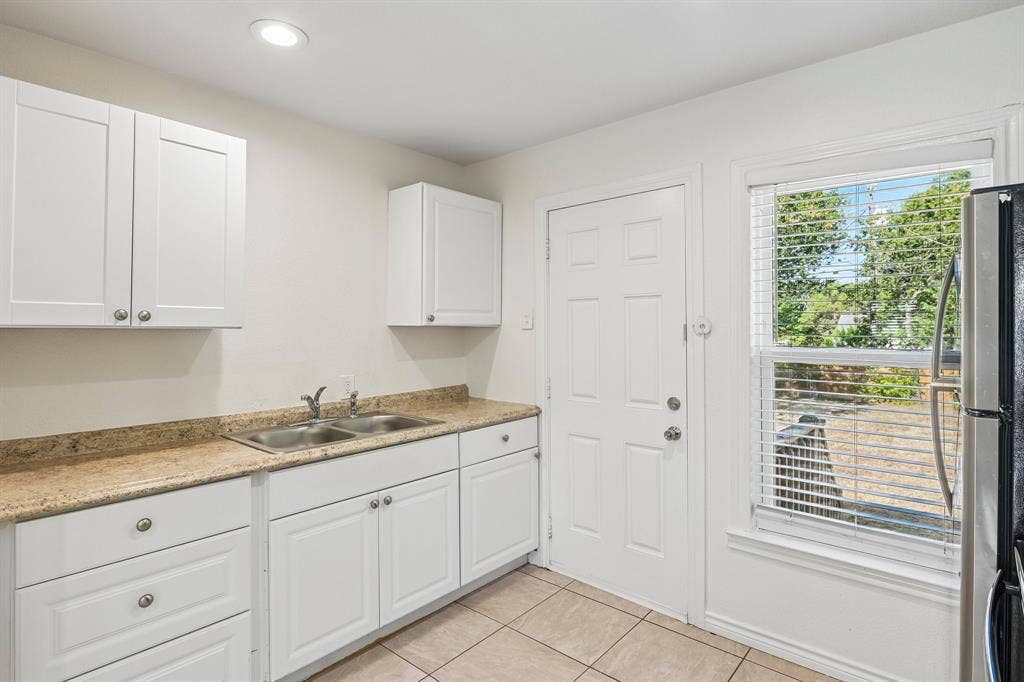 5012 Pamela Drive, Fort Worth, TX 76116 White upper and lower cabinetry, dual basin stainless steel sink, light-toned countertop, and recessed ceiling lighting