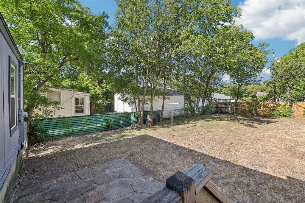5012 Pamela Drive, Fort Worth, TX 76116 Expansive backyard with a stone patio, established trees, and a partial privacy fence