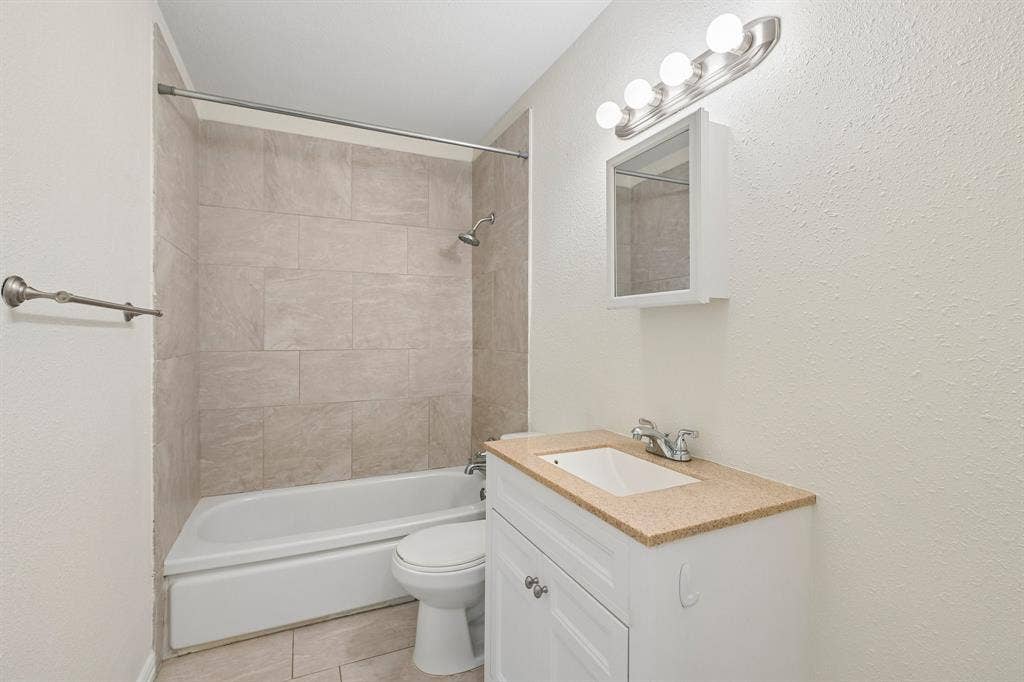 5012 Pamela Drive, Fort Worth, TX 76116 Bathroom featuring a white vanity with a light-toned countertop, a mounted medicine cabinet, and a tiled shower/tub combination