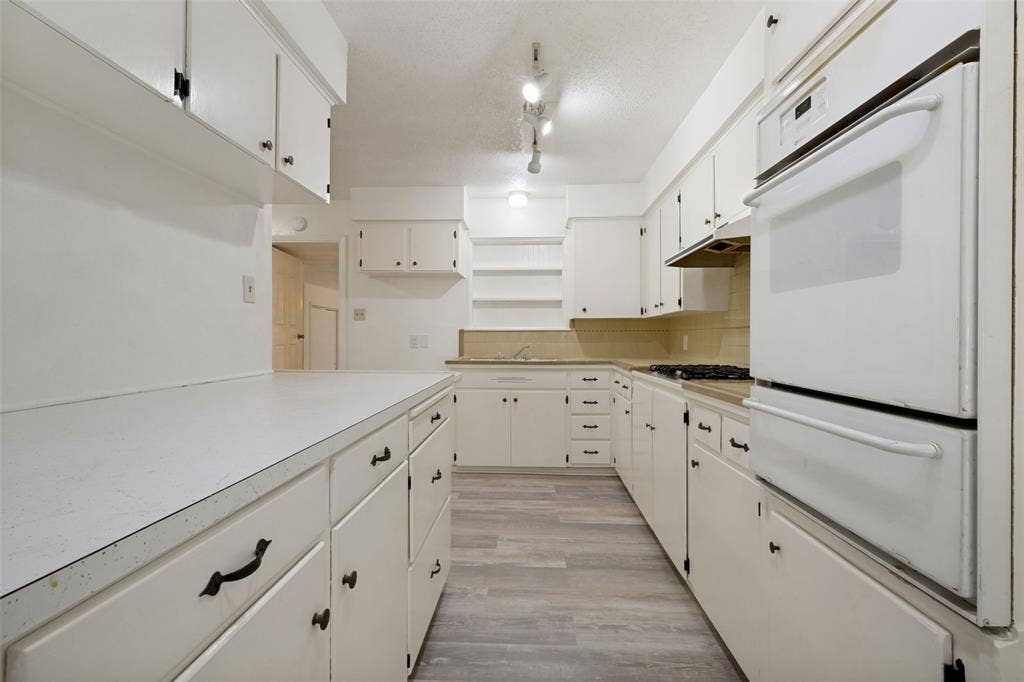 3214 Avon Street, Denton, TX 76209 Kitchen featuring white cabinetry, light-toned countertops, wood-finish flooring, a built-in oven, and a gas cooktop