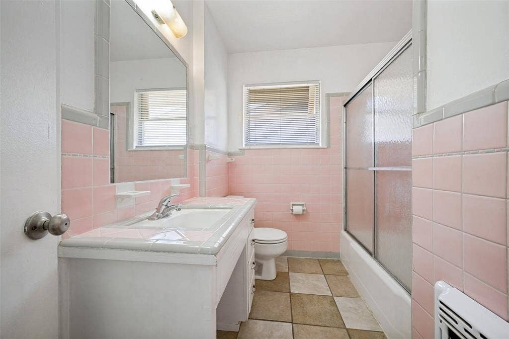 3214 Avon Street, Denton, TX 76209 Bathroom featuring pink ceramic wall tiles, a vanity with an integrated sink, a built-in mirror, a sliding glass shower enclosure, and checkerboard floor tiles