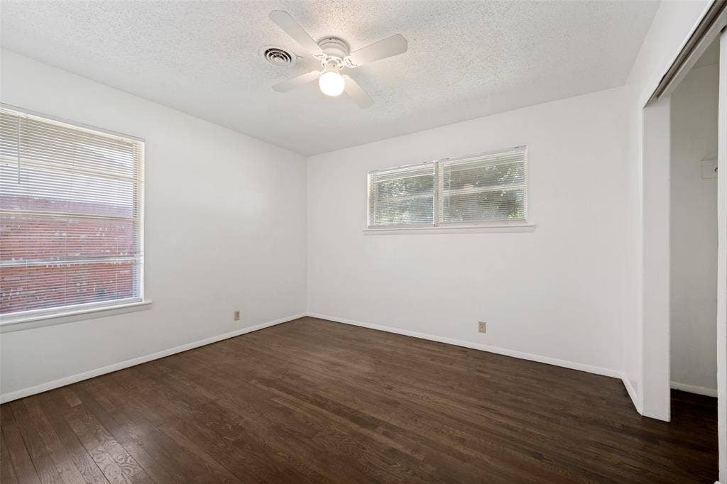 3214 Avon Street, Denton, TX 76209 Wood-finish flooring, white walls, two windows with blinds, and a ceiling fan with integrated lighting