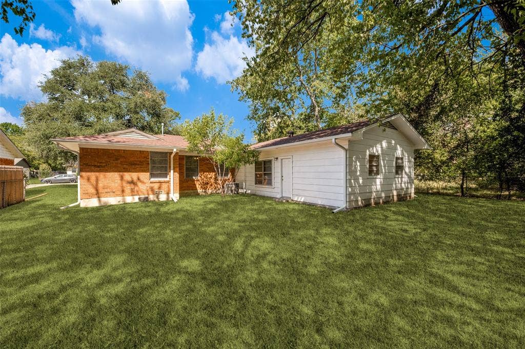 3214 Avon Street, Denton, TX 76209 Expansive green lawn with mature trees, brick exterior, and a detached structure with siding