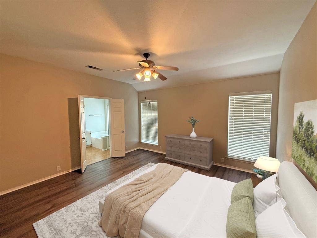 Vaulted ceiling with a ceiling fan, wood-finish flooring, and two windows with blinds