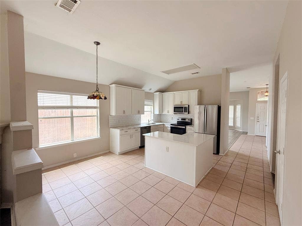 Kitchen featuring white cabinetry, stainless steel appliances, a center island, and tile flooring