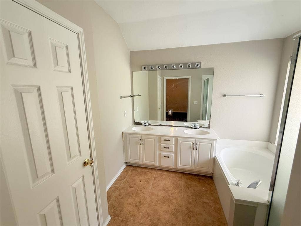 Dual basin vanity with white cabinetry and integrated sinks, complemented by a large wall-mounted mirror