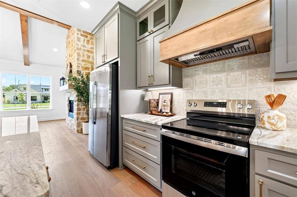 305 Grace Lane, Athens, TX 75751 Stainless steel appliances, light wood-finish flooring, stone-clad fireplace, vaulted ceiling with exposed beam, and patterned backsplash