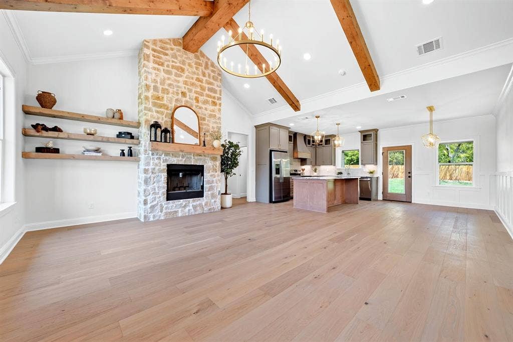 305 Grace Lane, Athens, TX 75751 Vaulted ceiling with exposed wood beams, stone-faced fireplace, wood-finish flooring, built-in shelving, and a kitchen island with built-in cabinetry