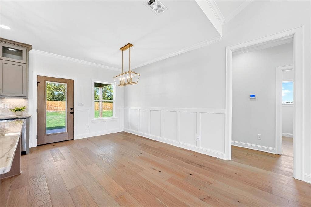 305 Grace Lane, Athens, TX 75751 Wood-finish flooring throughout, board and batten wall detailing, crown molding, and a gold-finish chandelier