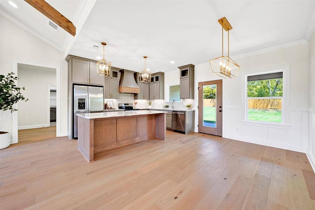 305 Grace Lane, Athens, TX 75751 Open concept kitchen and dining area featuring wood-finish flooring, a kitchen island with stone countertop, stainless steel appliances, and ceiling-mounted light fixtures