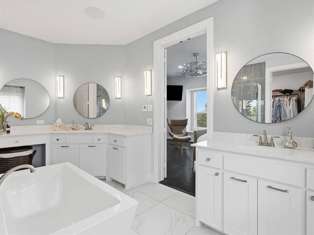 3505 Wycliff Avenue, McKinney, TX 75071 White soaking tub with deck-mounted faucet, dual vanities with round mirrors, and wall-mounted sconces