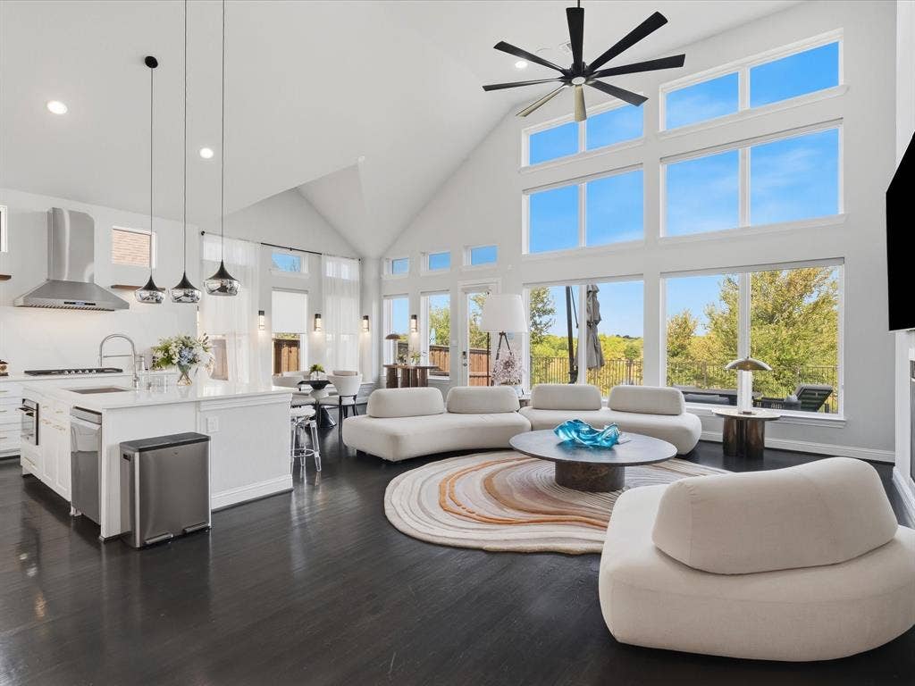 3505 Wycliff Avenue, McKinney, TX 75071 Vaulted ceilings with an exposed beam, a full wall of windows, a kitchen island with seating, dark wood-finish flooring, and pendant lighting