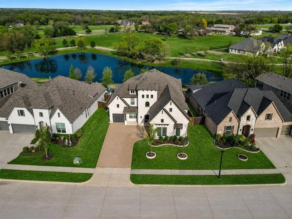 3505 Wycliff Avenue, McKinney, TX 75071 Expansive property featuring a large pond, lush green landscaping, a paved driveway, and a two-story home with a multi-gabled roof