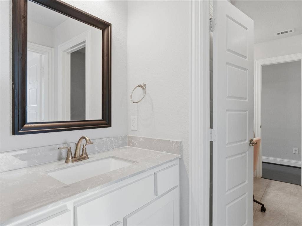 3505 Wycliff Avenue, McKinney, TX 75071 White vanity with an integrated sink, light-toned countertop, and framed mirror