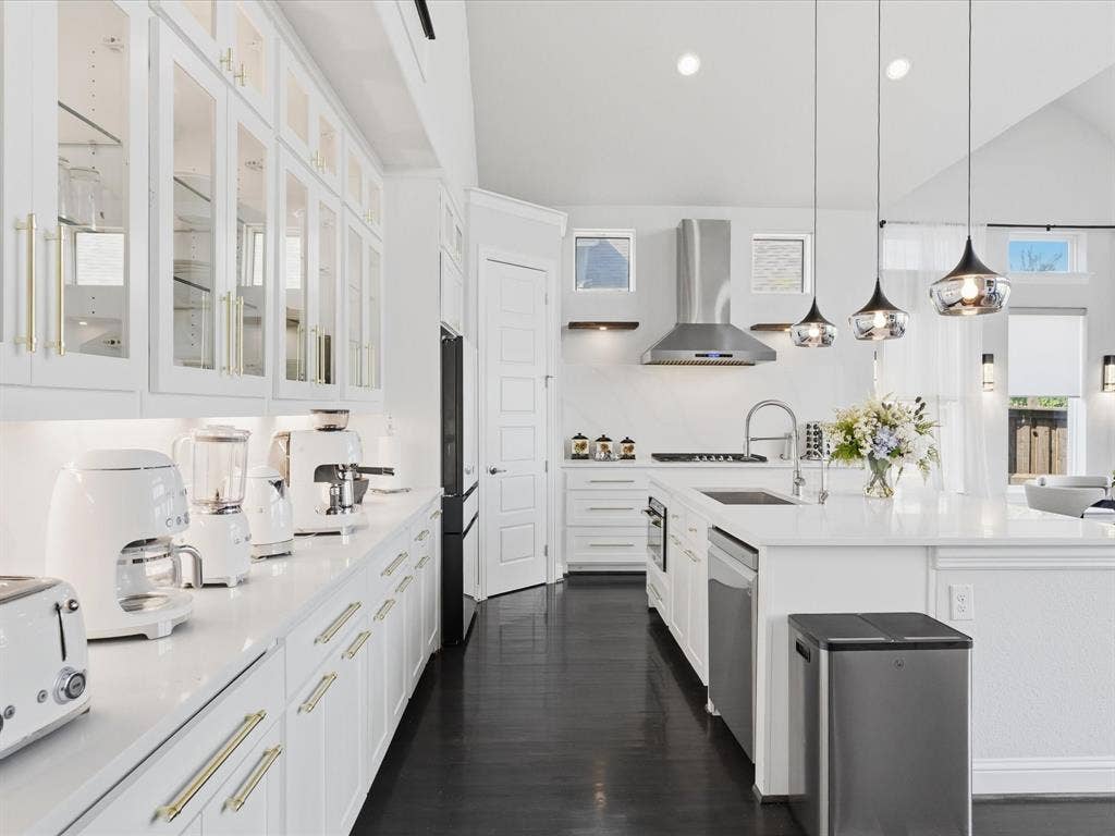 3505 Wycliff Avenue, McKinney, TX 75071 Open-concept kitchen with crisp white cabinetry, gold-finish hardware, stainless steel appliances, and a central island with an integrated sink