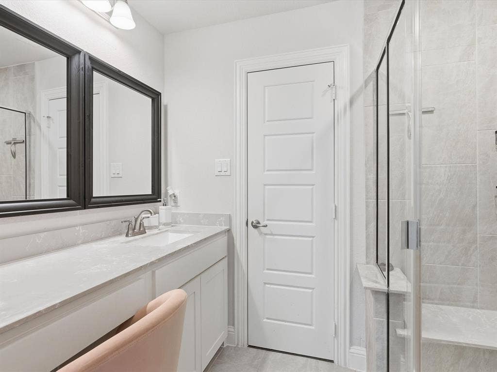 3505 Wycliff Avenue, McKinney, TX 75071 Dual framed mirrors, vanity with integrated sink, glass-enclosed shower, tiled shower walls, and a built-in shower bench