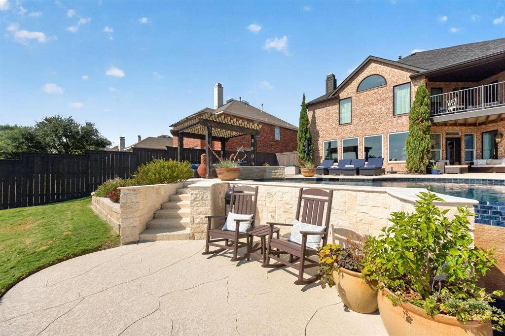 4016 Stone Haven Drive, Garland, TX 75043 Expansive backyard featuring a custom pool, tiered stone retaining walls, a stamped concrete patio, and a privacy fence