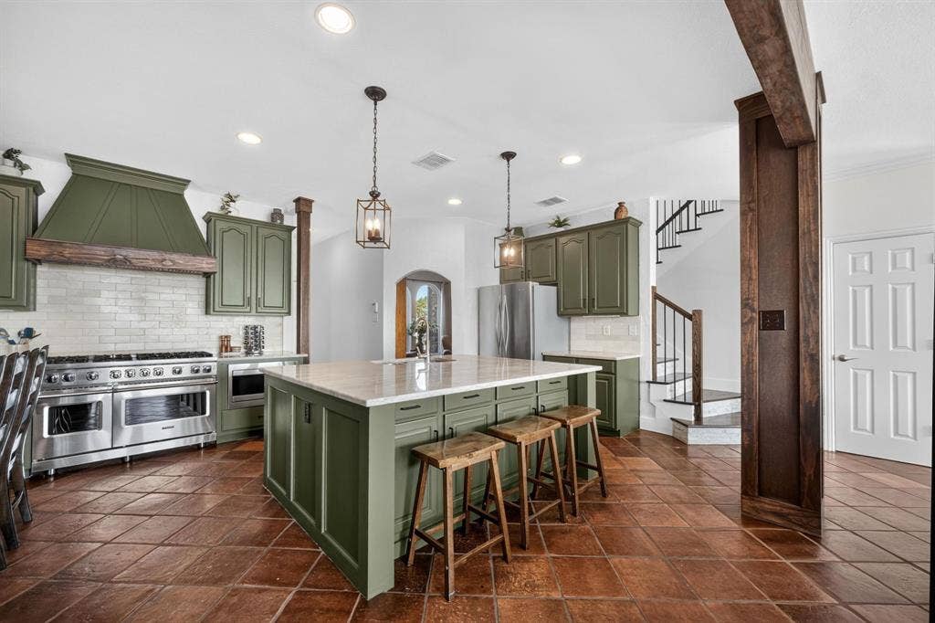 4016 Stone Haven Drive, Garland, TX 75043 Spacious kitchen featuring an expansive center island, paneled cabinetry, stainless steel appliances, and a tile backsplash