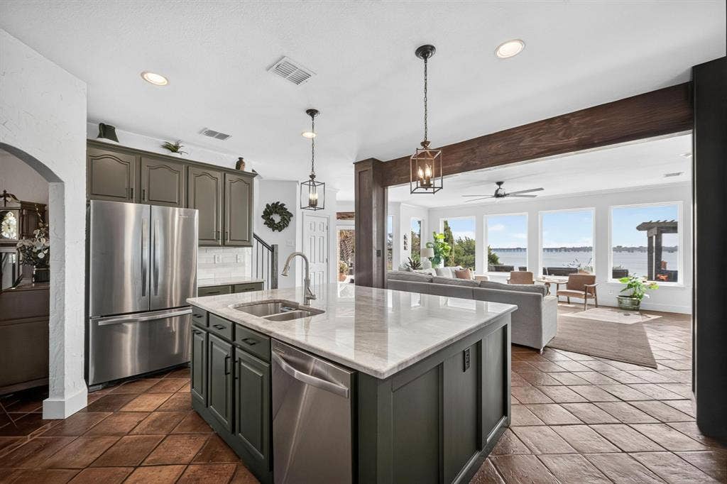 4016 Stone Haven Drive, Garland, TX 75043 Kitchen island with integrated double basin sink, dark cabinetry, and white countertop