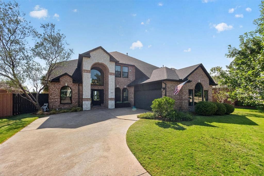 4016 Stone Haven Drive, Garland, TX 75043 Brick and stone facade, arched entryway, large arched window, attached garage, and a curved concrete driveway