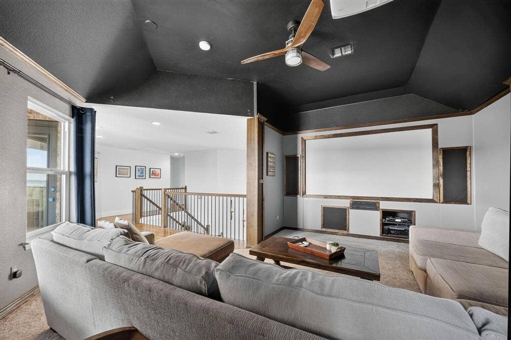 4016 Stone Haven Drive, Garland, TX 75043 Dedicated media room featuring a large projector screen, built-in media shelving, and a ceiling fan