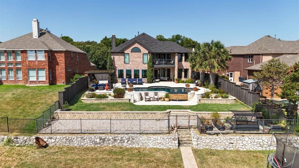 4016 Stone Haven Drive, Garland, TX 75043 Brick facade residence with a multi-level backyard featuring a swimming pool, stone retaining walls, and a manicured lawn