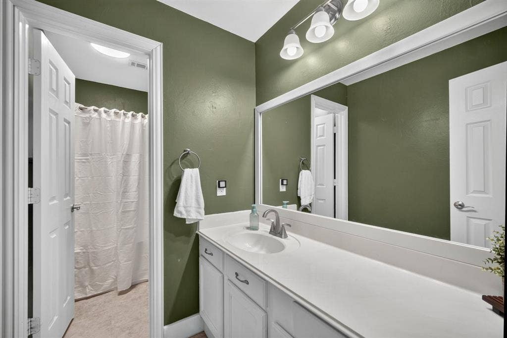 4016 Stone Haven Drive, Garland, TX 75043 Bathroom featuring a single vanity with an integrated sink, white cabinetry, and a full-width mirror