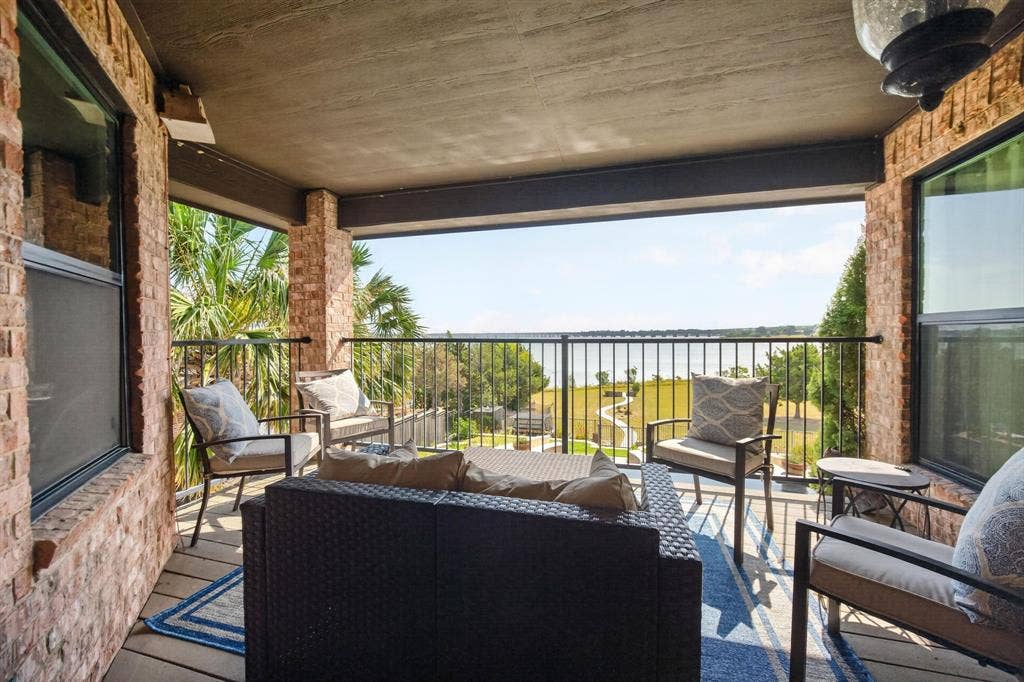 4016 Stone Haven Drive, Garland, TX 75043 Upstairs covered patio with a metal railing, overlooking a Lake Ray Hubbard, pool, and green landscape.