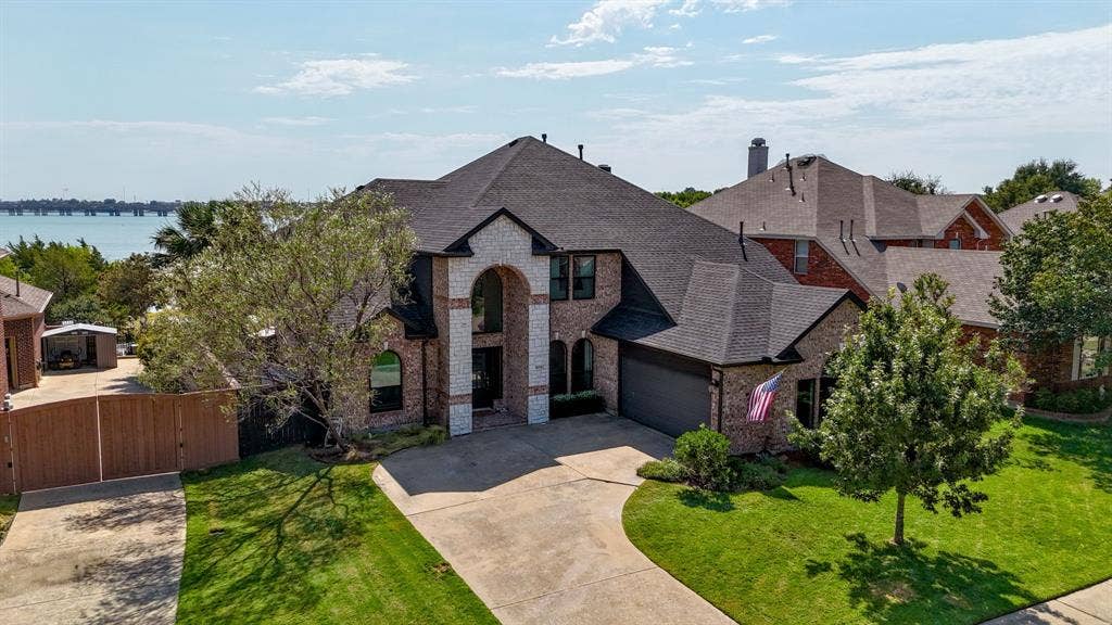 4016 Stone Haven Drive, Garland, TX 75043 Brick and stone facade with an arched entry, mature landscaping, and a two-car garage