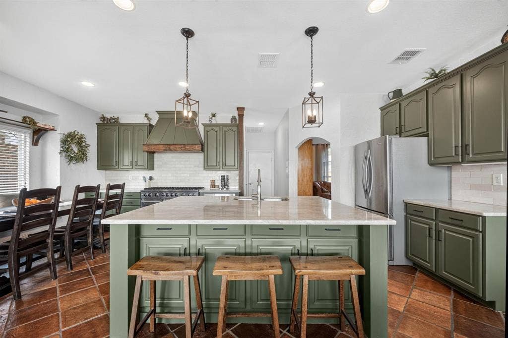 4016 Stone Haven Drive, Garland, TX 75043 Kitchen featuring green cabinetry, a central island with countertop seating, stainless steel appliances, and a tile backsplash